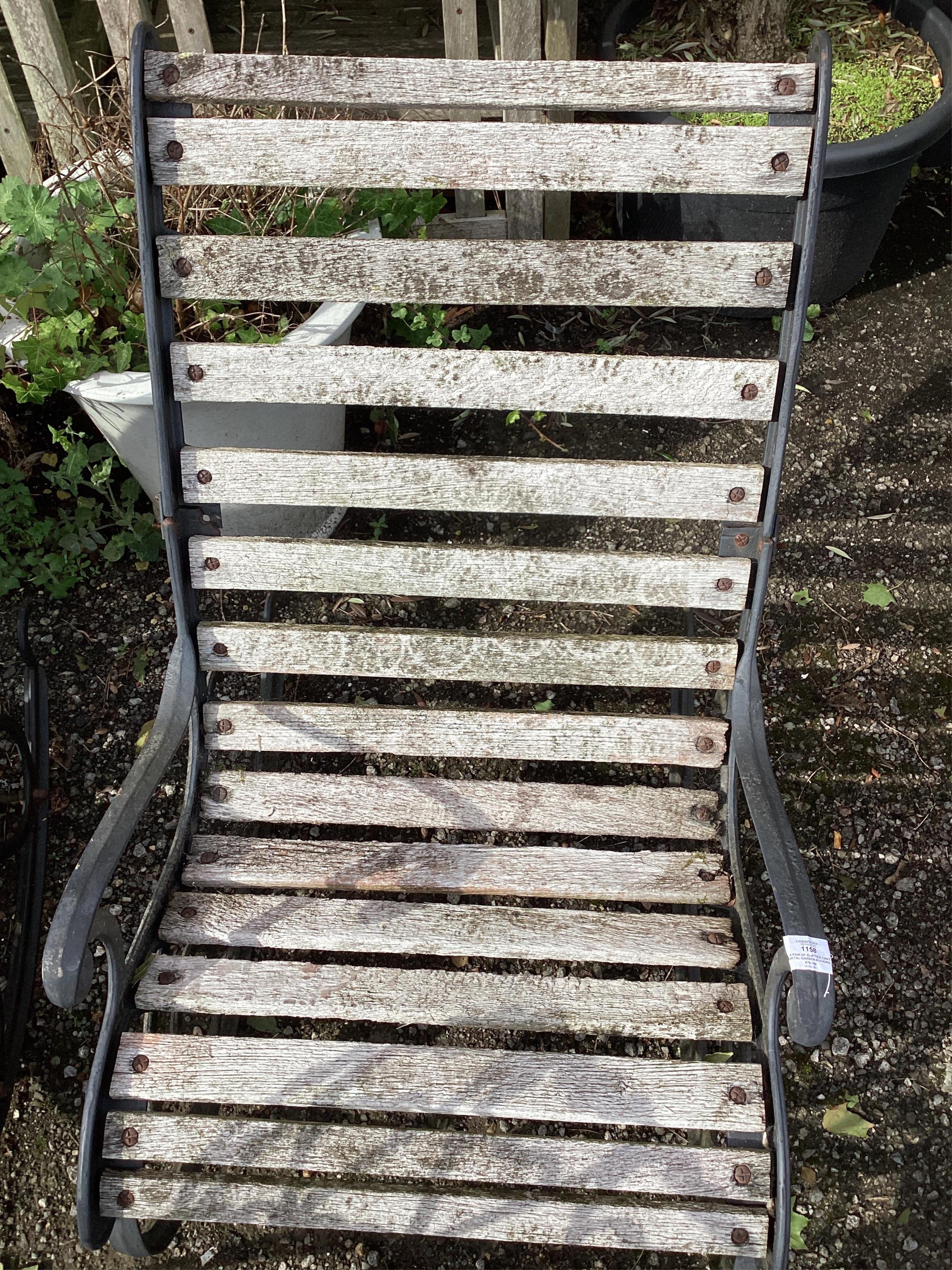 A pair of slatted cast metal garden rocking chairs